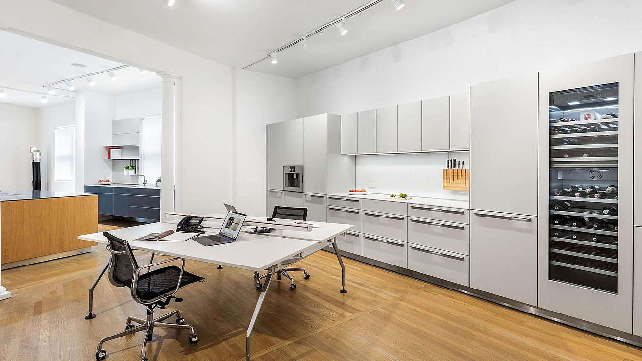 Office area with bulthaup b3 units in light grey laminate finish and integrated Gaggenau wine cooler and Gaggenau coffee machine. Central desk Vitra.