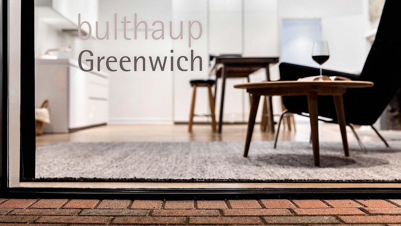 A glance through the window into the lounge area with the bulthaup Greenwich logo in close-up.
